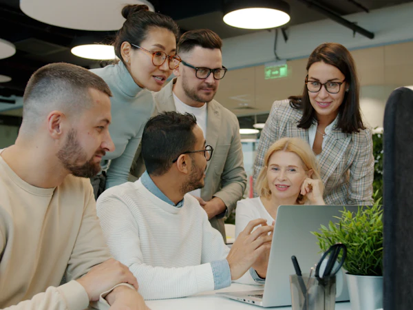 Team schaut gemeinsam und gut gelaunt auf einen Laptop